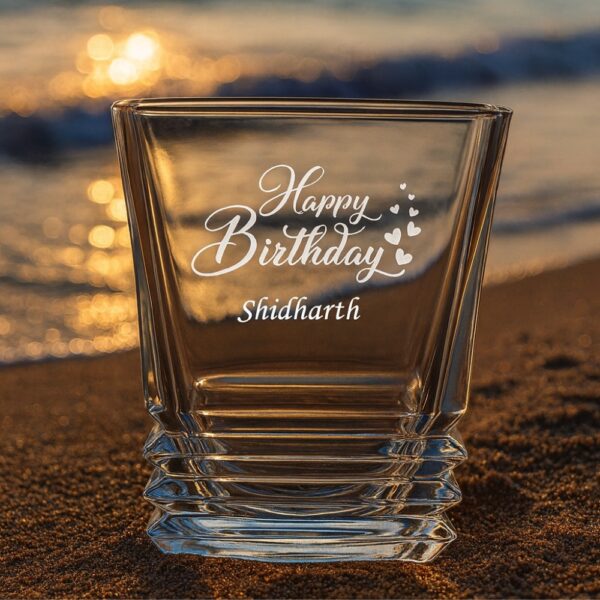 Personalized crystal whiskey glass with engraved “Happy Birthday” message, custom name Shidharth, filled with whiskey and ice cubes – unique engraved gift for birthdays and special occasions.