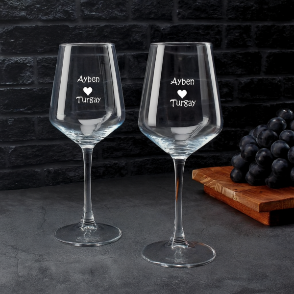 Elegant clear 465 ml wine glasses filled with red wine, laser engraved with custom names and a heart design, displayed on a dining table with flowers, plates, and a wine bottle—perfect personalized gift for Mother’s Day, birthdays, weddings, anniversaries, and special occasions.