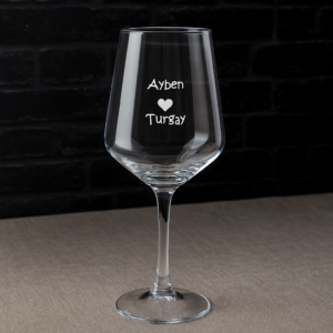 Elegant clear 465 ml wine glasses filled with red wine, laser engraved with custom names and a heart design, displayed on a dining table with flowers, plates, and a wine bottle—perfect personalized gift for Mother’s Day, birthdays, weddings, anniversaries, and special occasions.