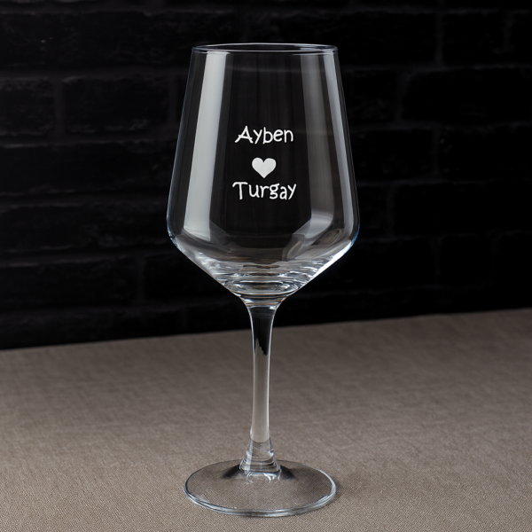 Elegant clear 465 ml wine glasses filled with red wine, laser engraved with custom names and a heart design, displayed on a dining table with flowers, plates, and a wine bottle—perfect personalized gift for Mother’s Day, birthdays, weddings, anniversaries, and special occasions.