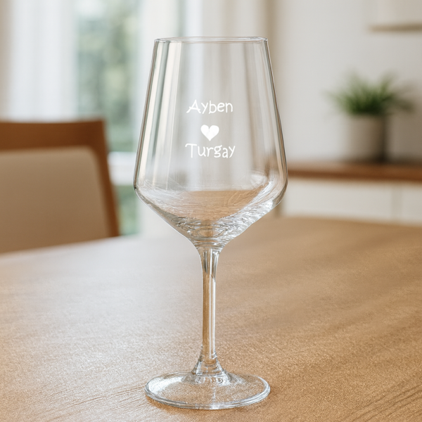 Elegant clear 465 ml wine glasses filled with red wine, laser engraved with custom names and a heart design, displayed on a dining table with flowers, plates, and a wine bottle—perfect personalized gift for Mother’s Day, birthdays, weddings, anniversaries, and special occasions.