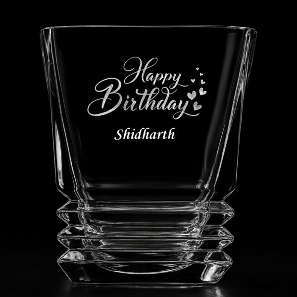 Personalized crystal whiskey glass with engraved “Happy Birthday” message, custom name Shidharth, filled with whiskey and ice cubes – unique engraved gift for birthdays and special occasions.