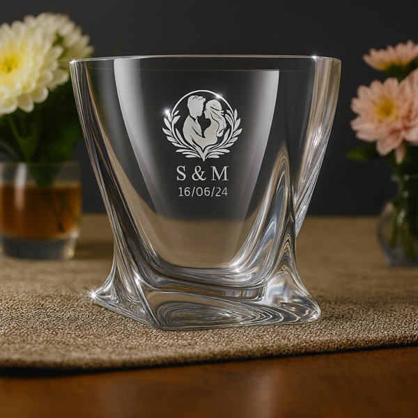Personalized crystal whiskey glass with twisted base design, engraved with couple silhouette inside a wreath, initials S & M, and date 16/06/24, filled with whiskey