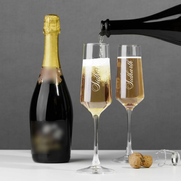 Elevate your special celebrations with these exquisite personalized champagne flutes. Each glass features a contemporary geometric design with an elegant, elongated stem that adds sophistication to any occasion. The crystal-clear glassware is enhanced with deep, precision-engraved customisation that maintains its beauty through countless toasts. These premium flutes come as a matching set of two, perfect for wedding ceremonies, anniversaries, or any momentous occasion. The modern angular bowl design helps preserve the bubbles while concentrating the champagne's aroma. The sturdy base ensures stability, whilst the tall, graceful stem allows for proper holding without warming the champagne. These bespoke glasses make for a treasured keepsake that couples can use to celebrate their special moments for years to come. Each flute is carefully crafted to hold the perfect amount of champagne, making them ideal for those celebratory toasts. The sophisticated design complements any table setting, from casual gatherings to formal events.