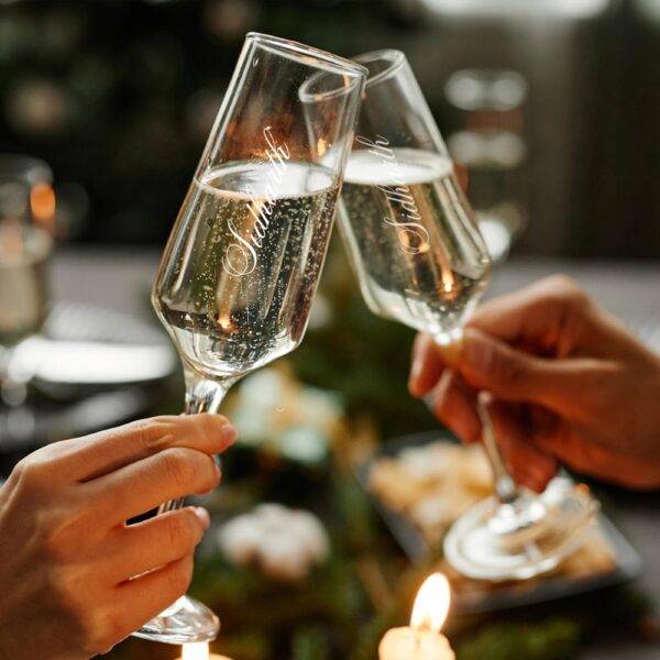 Elevate your special celebrations with these exquisite personalized champagne flutes. Each glass features a contemporary geometric design with an elegant, elongated stem that adds sophistication to any occasion. The crystal-clear glassware is enhanced with deep, precision-engraved customisation that maintains its beauty through countless toasts. These premium flutes come as a matching set of two, perfect for wedding ceremonies, anniversaries, or any momentous occasion. The modern angular bowl design helps preserve the bubbles while concentrating the champagne's aroma. The sturdy base ensures stability, whilst the tall, graceful stem allows for proper holding without warming the champagne. These bespoke glasses make for a treasured keepsake that couples can use to celebrate their special moments for years to come. Each flute is carefully crafted to hold the perfect amount of champagne, making them ideal for those celebratory toasts. The sophisticated design complements any table setting, from casual gatherings to formal events.