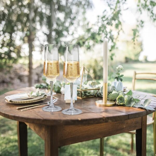 Elevate your special celebrations with these exquisite personalized champagne flutes. Each glass features a contemporary geometric design with an elegant, elongated stem that adds sophistication to any occasion. The crystal-clear glassware is enhanced with deep, precision-engraved customisation that maintains its beauty through countless toasts. These premium flutes come as a matching set of two, perfect for wedding ceremonies, anniversaries, or any momentous occasion. The modern angular bowl design helps preserve the bubbles while concentrating the champagne's aroma. The sturdy base ensures stability, whilst the tall, graceful stem allows for proper holding without warming the champagne. These bespoke glasses make for a treasured keepsake that couples can use to celebrate their special moments for years to come. Each flute is carefully crafted to hold the perfect amount of champagne, making them ideal for those celebratory toasts. The sophisticated design complements any table setting, from casual gatherings to formal events.