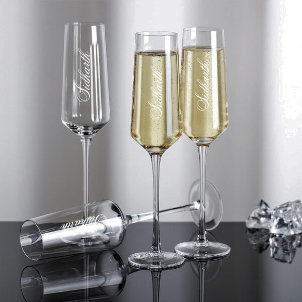 Elevate your special celebrations with these exquisite personalized champagne flutes. Each glass features a contemporary geometric design with an elegant, elongated stem that adds sophistication to any occasion. The crystal-clear glassware is enhanced with deep, precision-engraved customisation that maintains its beauty through countless toasts. These premium flutes come as a matching set of two, perfect for wedding ceremonies, anniversaries, or any momentous occasion. The modern angular bowl design helps preserve the bubbles while concentrating the champagne's aroma. The sturdy base ensures stability, whilst the tall, graceful stem allows for proper holding without warming the champagne. These bespoke glasses make for a treasured keepsake that couples can use to celebrate their special moments for years to come. Each flute is carefully crafted to hold the perfect amount of champagne, making them ideal for those celebratory toasts. The sophisticated design complements any table setting, from casual gatherings to formal events.