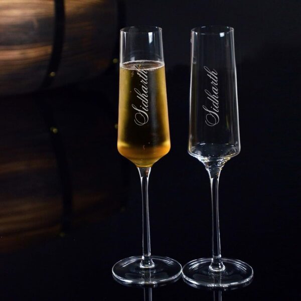 Elevate your special celebrations with these exquisite personalized champagne flutes. Each glass features a contemporary geometric design with an elegant, elongated stem that adds sophistication to any occasion. The crystal-clear glassware is enhanced with deep, precision-engraved customisation that maintains its beauty through countless toasts. These premium flutes come as a matching set of two, perfect for wedding ceremonies, anniversaries, or any momentous occasion. The modern angular bowl design helps preserve the bubbles while concentrating the champagne's aroma. The sturdy base ensures stability, whilst the tall, graceful stem allows for proper holding without warming the champagne. These bespoke glasses make for a treasured keepsake that couples can use to celebrate their special moments for years to come. Each flute is carefully crafted to hold the perfect amount of champagne, making them ideal for those celebratory toasts. The sophisticated design complements any table setting, from casual gatherings to formal events.