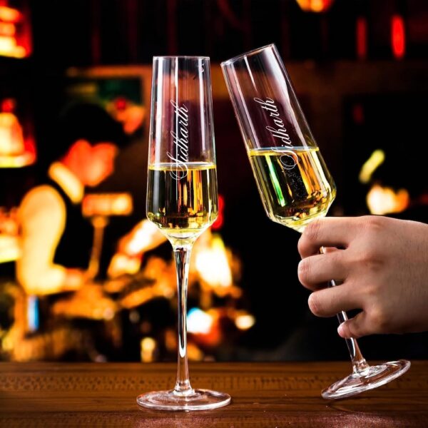 Elevate your special celebrations with these exquisite personalized champagne flutes. Each glass features a contemporary geometric design with an elegant, elongated stem that adds sophistication to any occasion. The crystal-clear glassware is enhanced with deep, precision-engraved customisation that maintains its beauty through countless toasts. These premium flutes come as a matching set of two, perfect for wedding ceremonies, anniversaries, or any momentous occasion. The modern angular bowl design helps preserve the bubbles while concentrating the champagne's aroma. The sturdy base ensures stability, whilst the tall, graceful stem allows for proper holding without warming the champagne. These bespoke glasses make for a treasured keepsake that couples can use to celebrate their special moments for years to come. Each flute is carefully crafted to hold the perfect amount of champagne, making them ideal for those celebratory toasts. The sophisticated design complements any table setting, from casual gatherings to formal events.