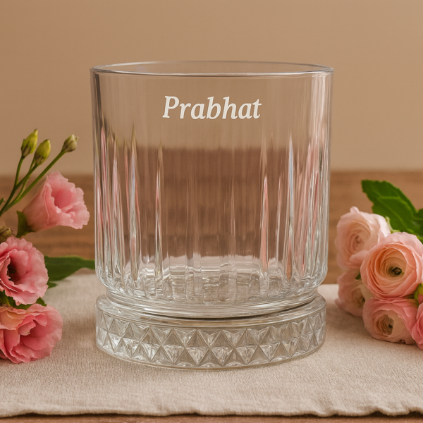 Personalized engraved whiskey glass with name 'Prabhat' on the side and bottom message 'I Promise to Always Be by Your Side', displayed outdoors on grass