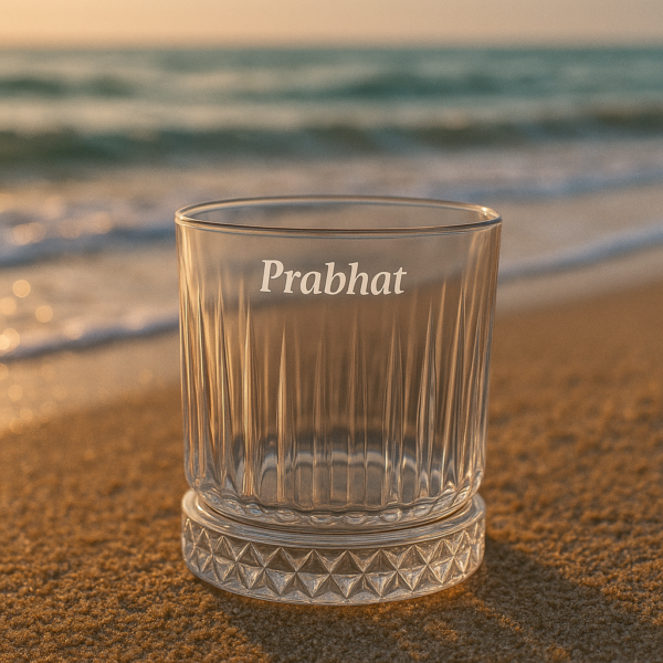 Personalized engraved whiskey glass with name 'Prabhat' on the side and bottom message 'I Promise to Always Be by Your Side', displayed outdoors on grass