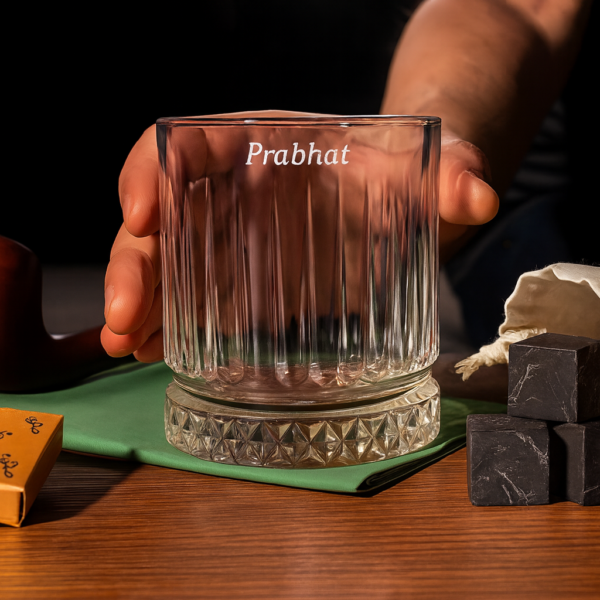 Personalized engraved whiskey glass with name 'Prabhat' on the side and bottom message 'I Promise to Always Be by Your Side', displayed outdoors on grass