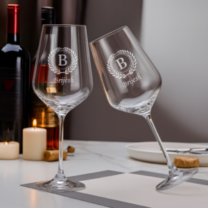 Close-up of an elegant 435 ml crystal wine glass featuring deep-etched custom engraving—a decorative laurel wreath encircling a bold initial and personalized name—designed as a refined and meaningful gift.