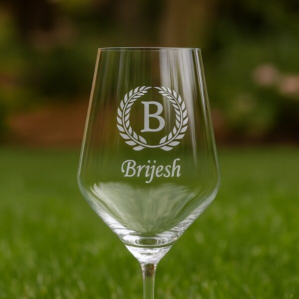 Close-up of an elegant 435 ml crystal wine glass featuring deep-etched custom engraving—a decorative laurel wreath encircling a bold initial and personalized name—designed as a refined and meaningful gift.